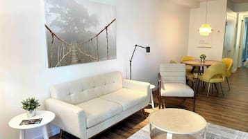 Uma sala de estar moderna com um sofá, uma mesa de centro e um espaço de jantar com cadeiras amarelas.