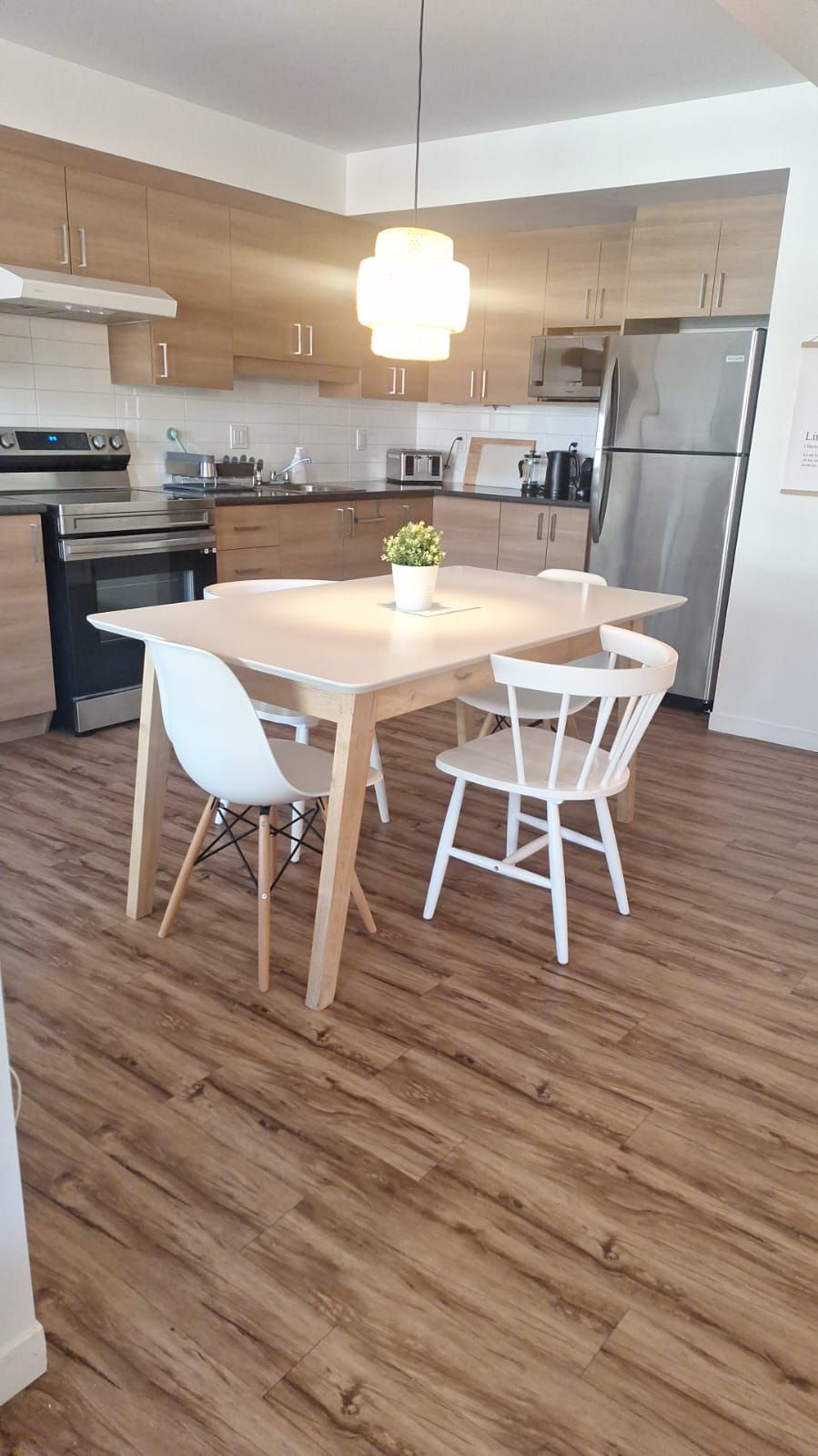 A modern kitchen with wooden cabinets, stainless steel appliances, and a central island with chairs.