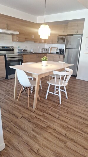 Una cocina moderna con armarios de madera, electrodomésticos de acero inoxidable y una isla central con sillas.