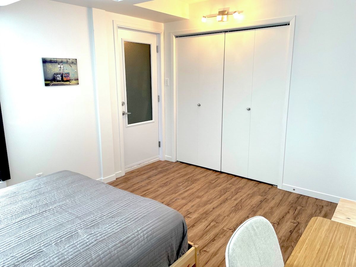 A bedroom with a bed, a desk, a chair, a wardrobe, and a door.
