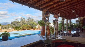 A poolside area with a pergola, outdoor seating, and a view of a mountain range.