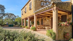 A stone building with a covered patio, outdoor seating, and air conditioning units.