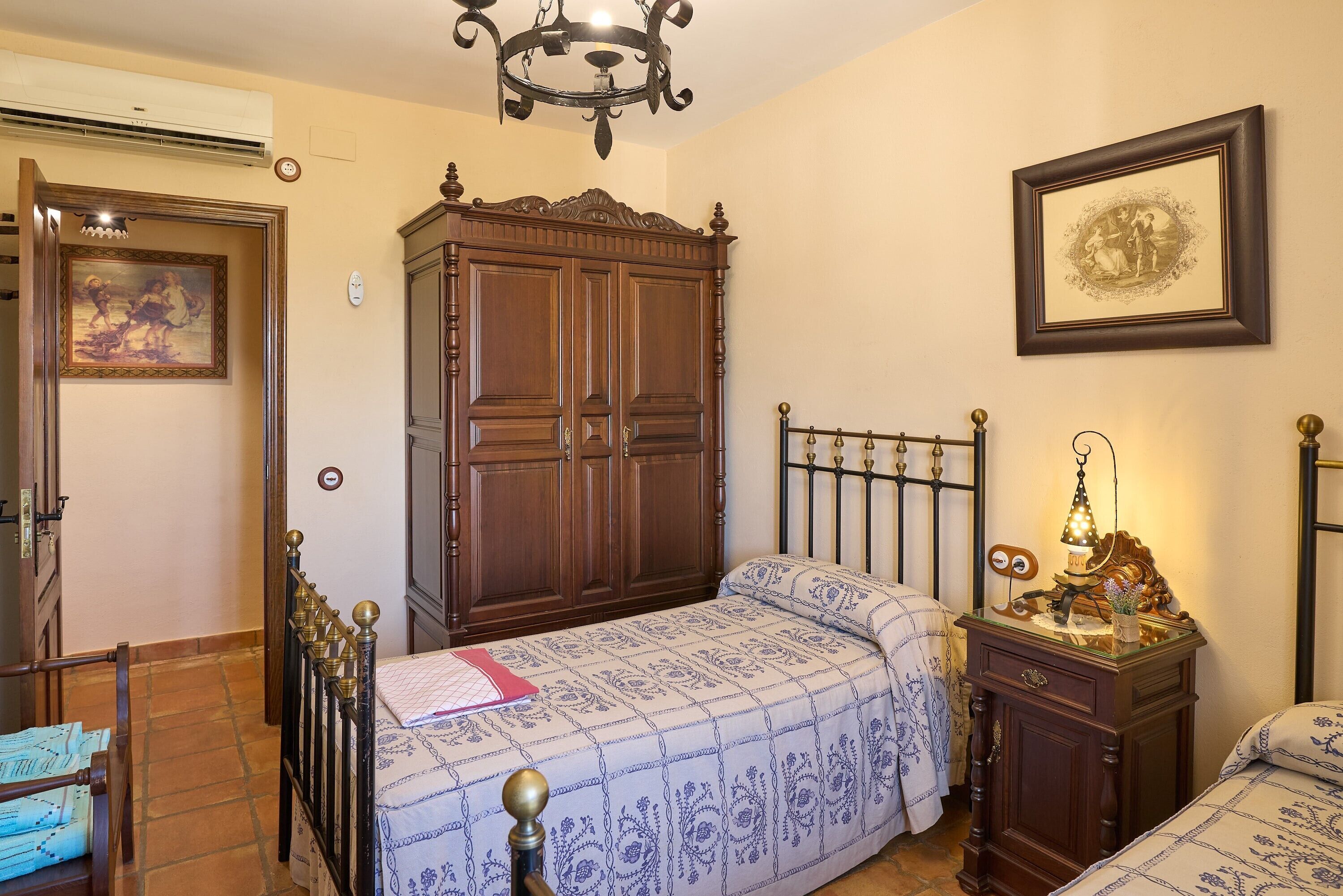 Een slaapkamer met een bed, een kledingkast en een kroonluchter.