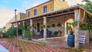 A stone building with a covered patio, outdoor seating, and potted plants.
