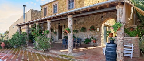 A stone building with a covered patio, outdoor seating, and potted plants.