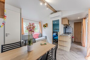 Una cocina compacta con estufa integrada, una zona de comedor con mesa de madera y un espacio de estar con banco.