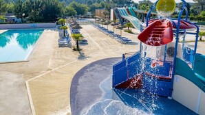 Un parc aquatique avec une piscine, des toboggans et un espace de jeux aquatiques.