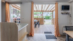Une cuisine moderne avec un plan de travail en bois, un four encastré et une fenêtre agrémentée de rideaux orange.