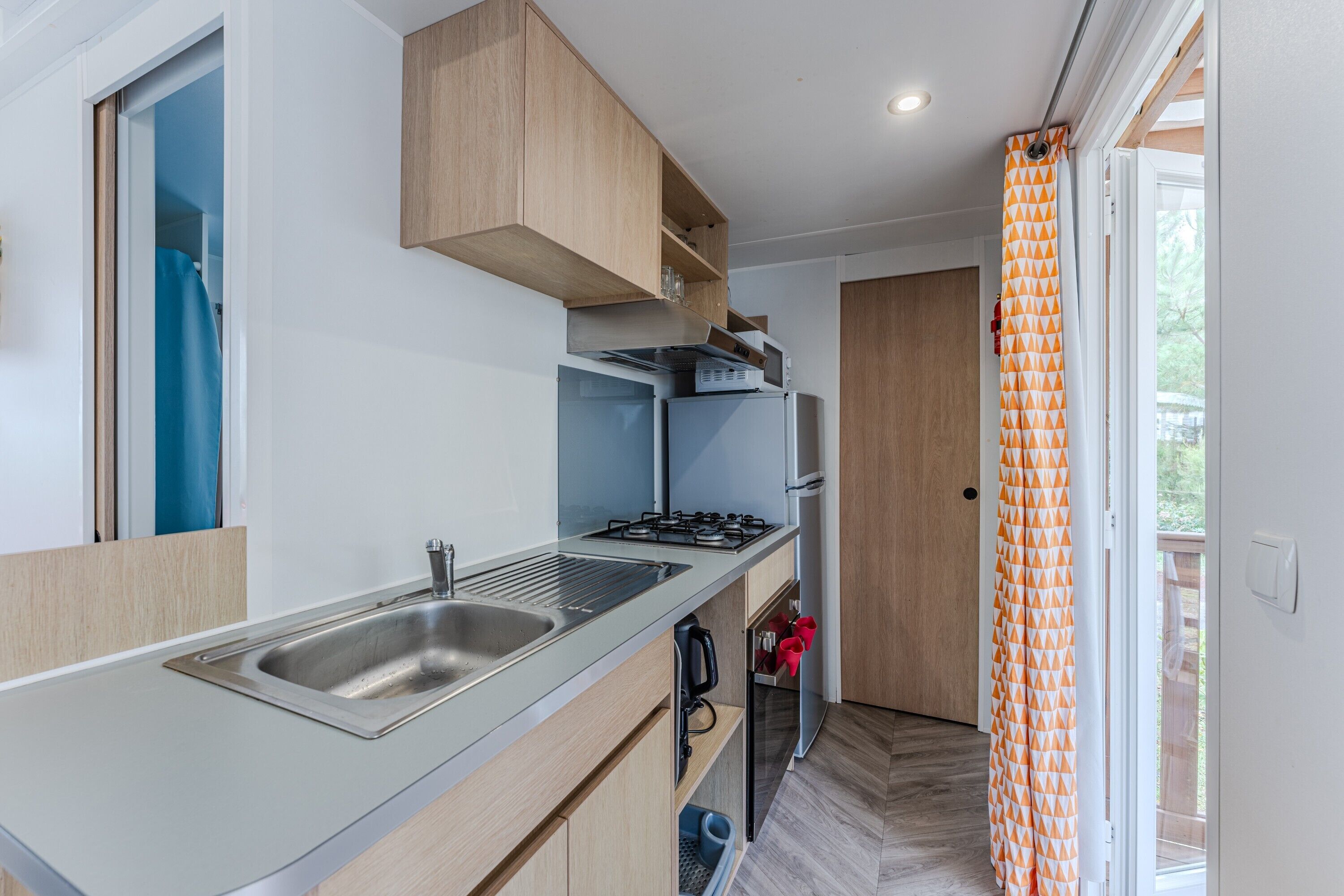 A compact kitchen with a built-in gas stove, a sink, and a small refrigerator.