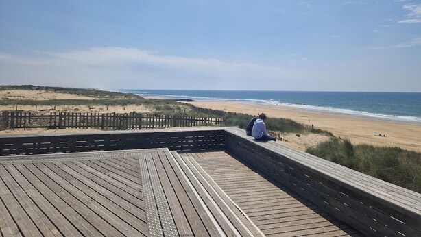 Une terrasse en bois offrant une vue sur la plage et l’océan.