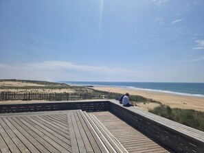 Una terraza de madera con vista a la playa y al océano.