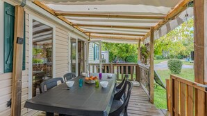 A covered patio with a table set for dining, outdoor seating, and a view of the backyard.