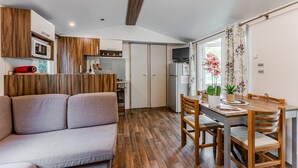 A compact kitchen with wooden cabinets, a microwave, and a dining area with a table and chairs.