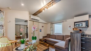 A modern living room with a sofa, dining table, and a microwave.