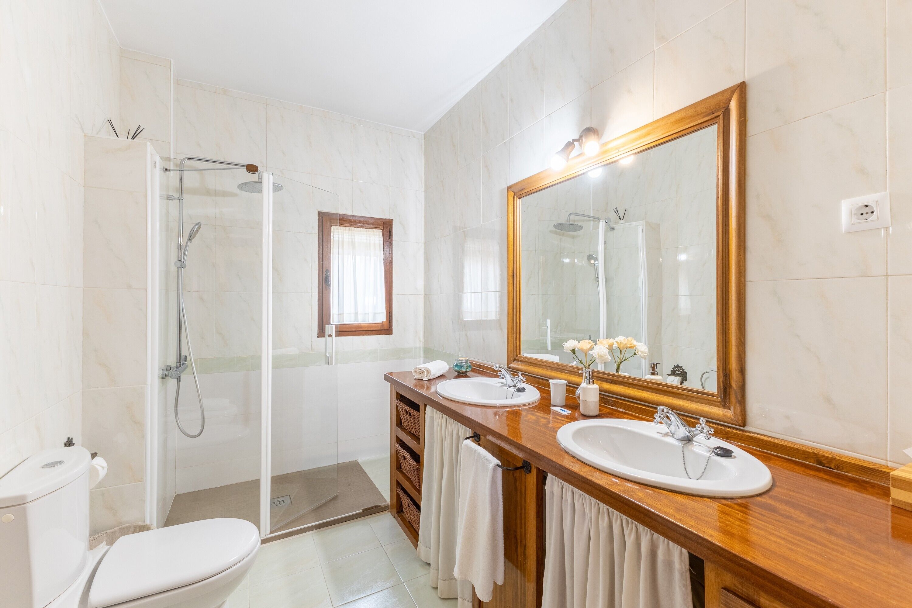 Une salle de bain avec une douche, deux lavabos, un grand miroir et des toilettes.