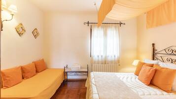 A bedroom with two beds, a radiator, a window with curtains, and wall-mounted lamps.