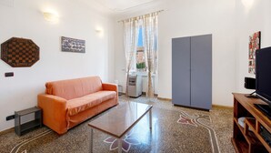 Olohuoneessa on sohva, sohvapöytä, televisio ja vaatekaappi.