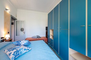 Une chambre à coucher avec un lit, deux oreillers, une table de chevet, une lampe, une armoire et une porte.