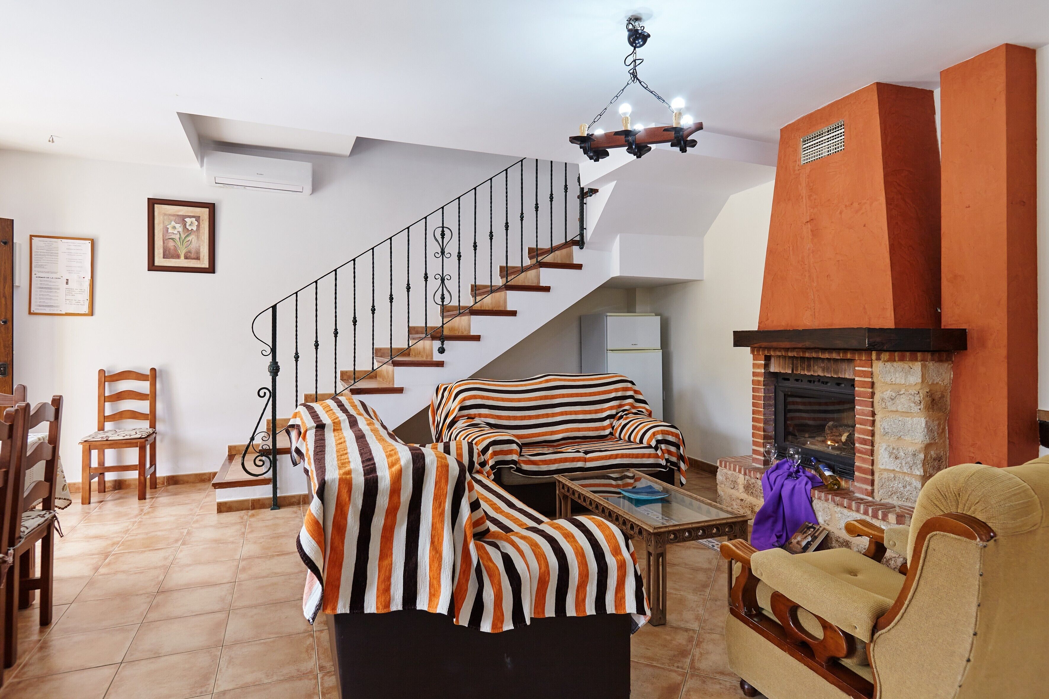 Un salon avec un escalier, une cheminée et des meubles à rayures.