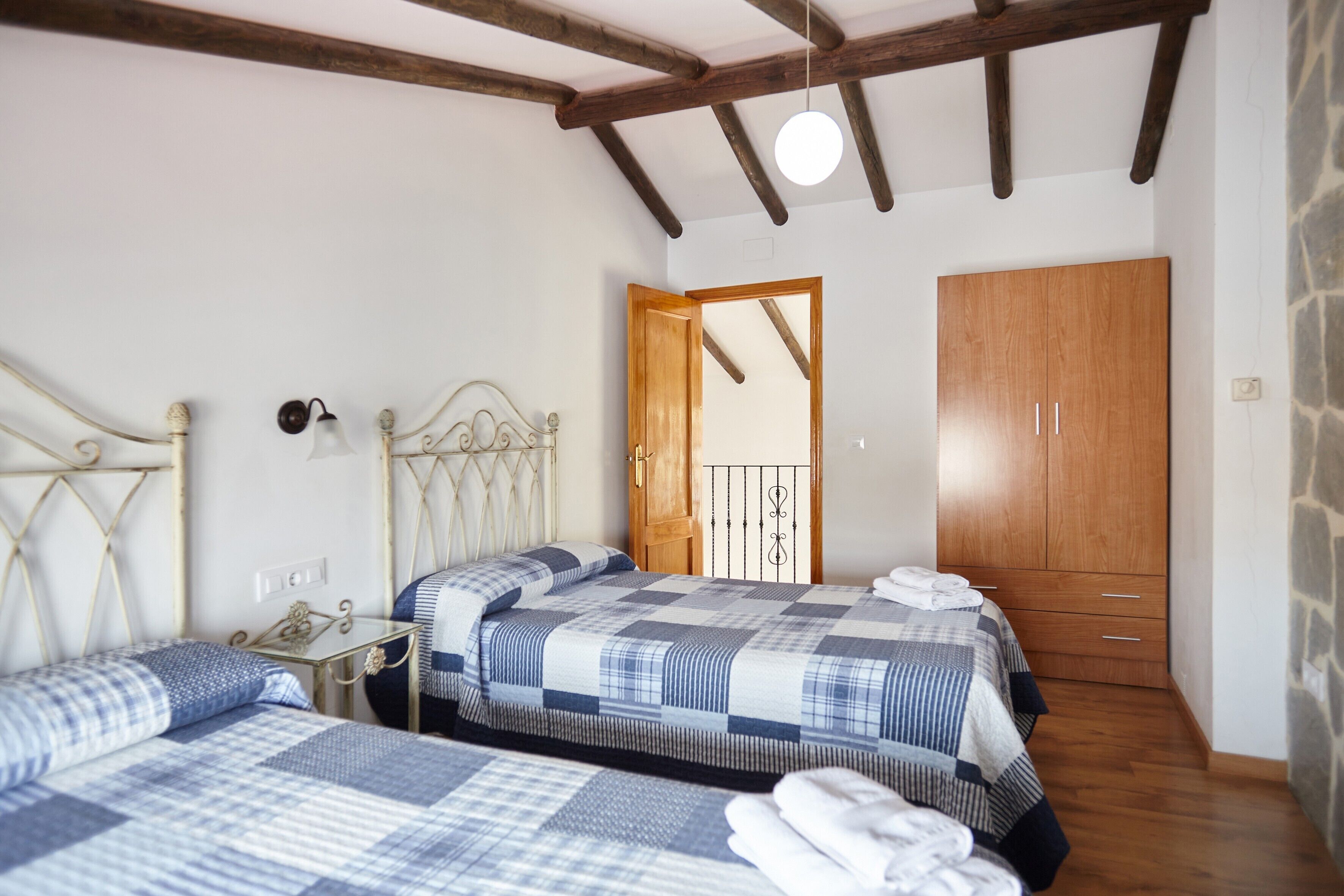 Een slaapkamer met twee bedden, een houten garderobe, een nachtkastje en een spiegel.