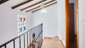A staircase with a wooden handrail, a hanging light fixture, and a stained glass window.