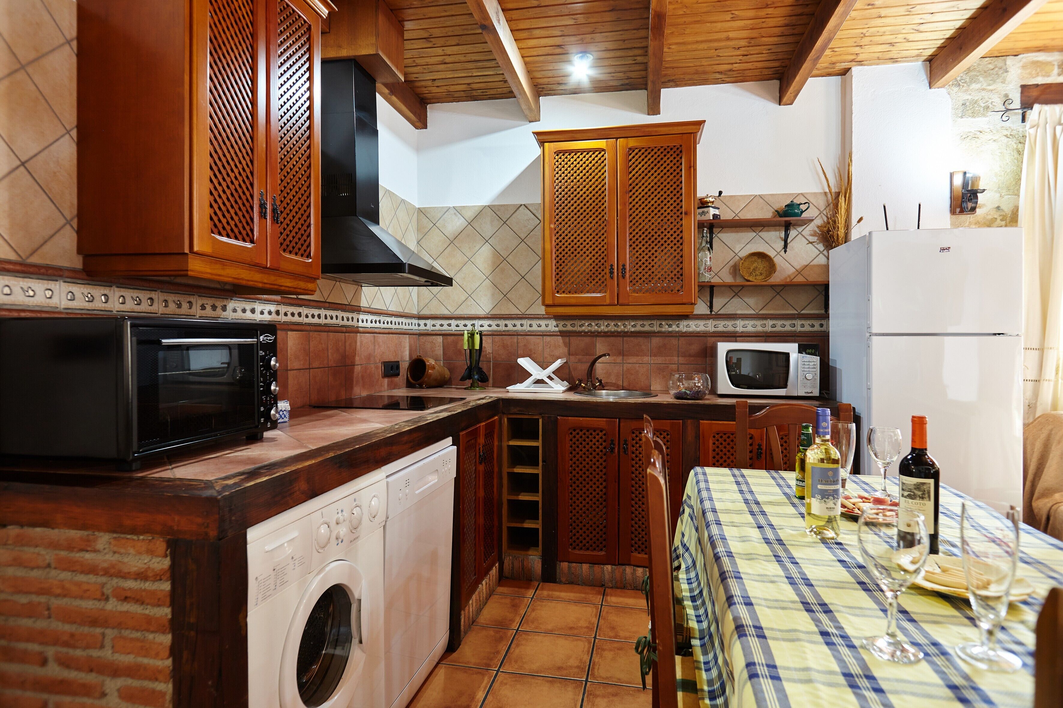 A kitchen with a washing machine, microwave, and wooden cabinets.