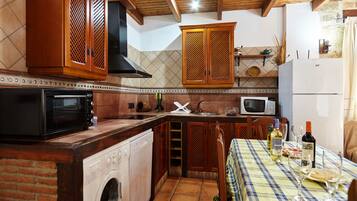 A kitchen with a washing machine, microwave, and wooden cabinets.