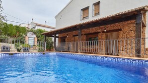 Une piscine dont le bord est revêtu de carreaux, avec un mur en pierre et un garde-corps en métal.