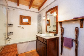 A bathroom with a bathtub, a sink, a mirror, and a towel rack.
