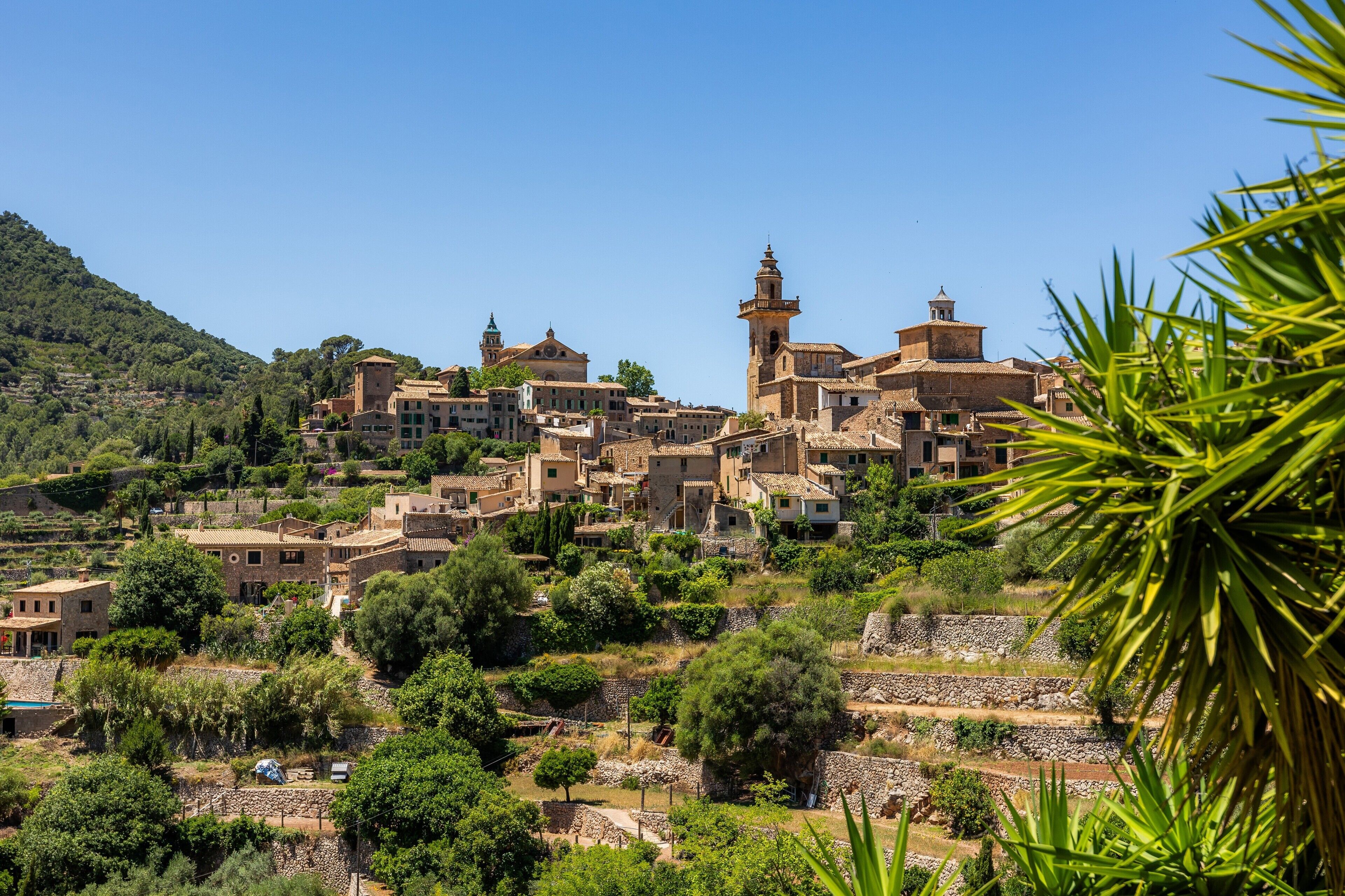 Un borgo collinare con architettura tradizionale, campi a terrazze e un campanile imponente.