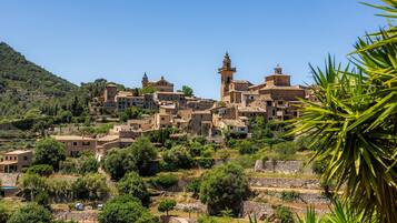 Un borgo collinare con architettura tradizionale, campi a terrazze e un campanile imponente.