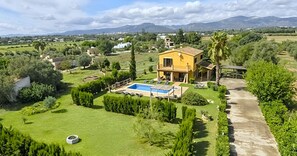 Una casa con piscina, circondata da vegetazione rigogliosa e montagne sullo sfondo.