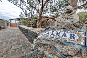 A stone pathway leading to a building with a 'Welcome' sign and a 'Calmar' sign. - 'Villalmar' with Sea View, Private Pool and Wi-Fi (Caleta de Famara)