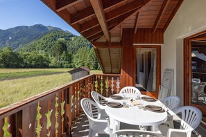 A balcony with a table set for dining, overlooking a mountainous landscape.