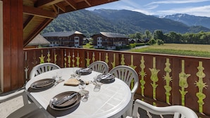 Ein Tisch ist für ein Essen gedeckt, mit Blick auf eine Berglandschaft im Hintergrund.