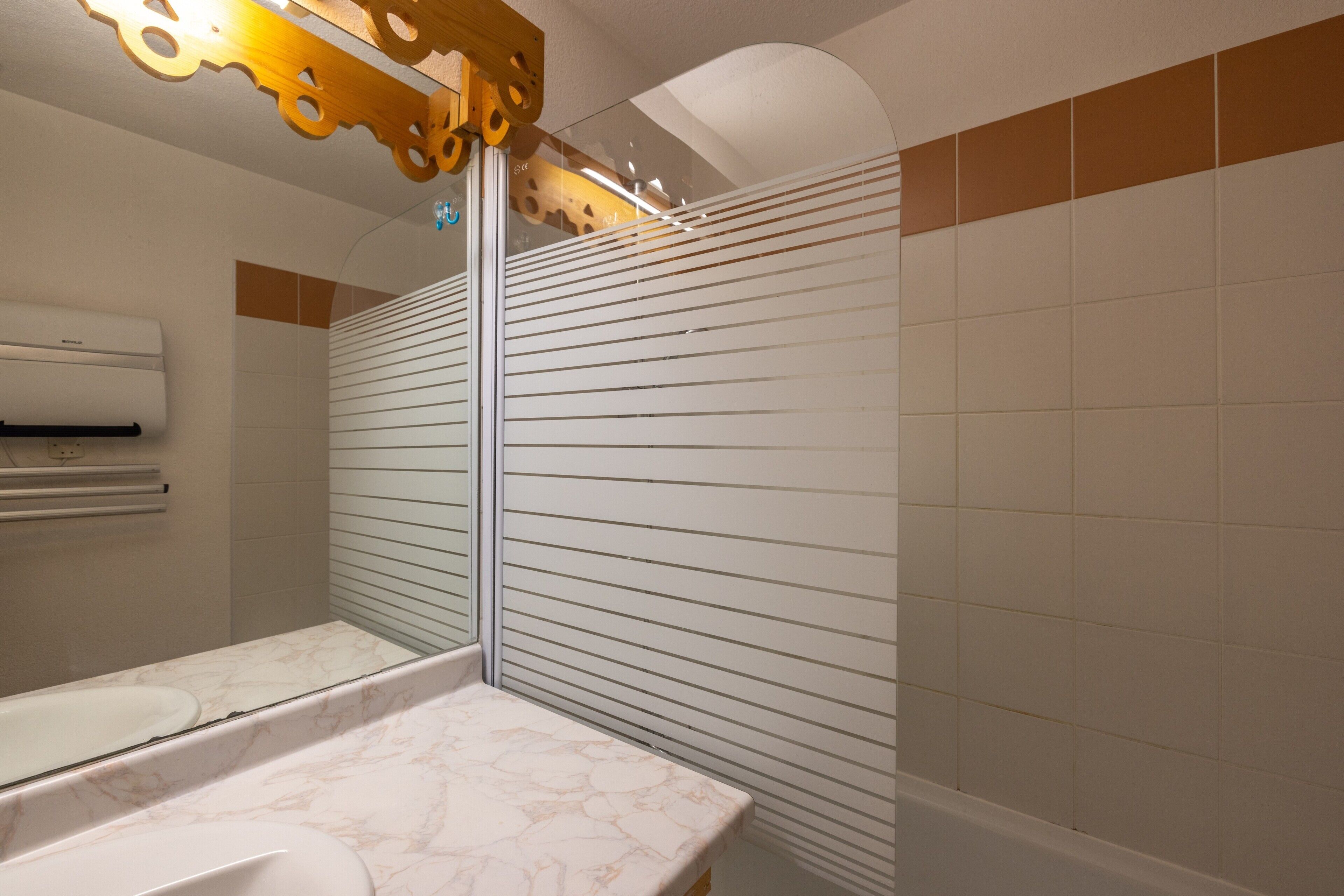 A bathroom with a marble countertop, a wall-mounted air conditioner, and a mirror.