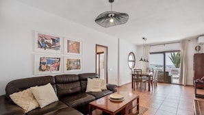 A living room with a brown leather sofa, a wooden coffee table, and artwork on the walls.