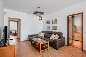 Ein Wohnzimmer mit Sofa, Couchtisch, Fernseher und Kunstwerk an der Wand.