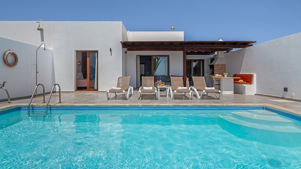 A swimming pool with lounge chairs and a covered seating area.