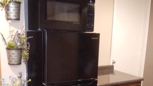 A black refrigerator with a microwave on top, wooden cabinets, and two potted plants on the wall. - Studio, sleeps 4, patio, short drive to Ski Resort, Six Flags & concert venues (Ballwin)
