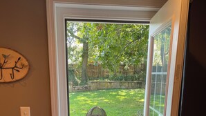 A door leading to a backyard with a wooden deck, a metal bench, and a stone wall. - Studio, sleeps 4, patio, short drive to Ski Resort, Six Flags & concert venues (Ballwin)