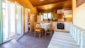 A cabin interior with a dining area, kitchenette, and a bed.