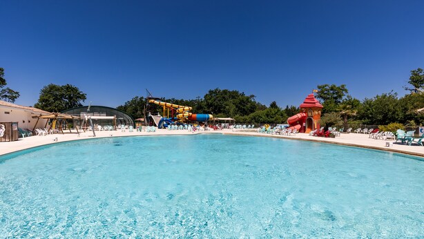A large swimming pool with a water slide and a red tower structure.