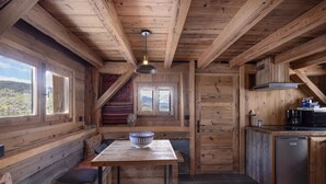 Interior de madera con banco, mesa y zona de cocina.