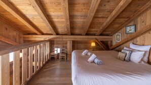 Una habitación de madera con una cama, un escritorio y sillas.