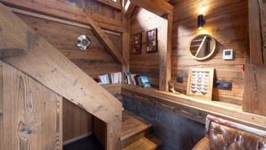 A wooden interior with a staircase, bookshelves, and a mirror. - Chalet 'Mazot Des Aravis' with Mountain View, Private Terrace and Private Garden (Combloux)