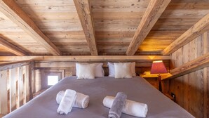 A wooden room with a bed, pillows, and a lamp. - Chalet 'Mazot Des Aravis' with Mountain View, Private Terrace and Private Garden (Combloux)