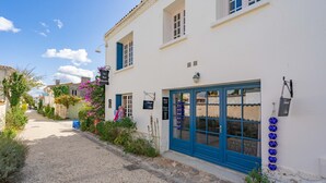 Una estrecha calle empedrada con un edificio blanco que tiene una puerta azul y letreros que señalan un restaurante.