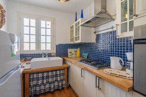 A kitchen with a sink, stove, cabinets, and a window.