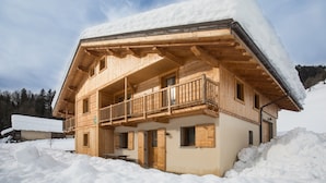 Una cabaña de madera con balcón, rodeada de nieve.